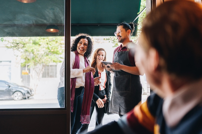 A smiling business team welcoming a new client at the office door, representing a professional and seamless onboarding experience