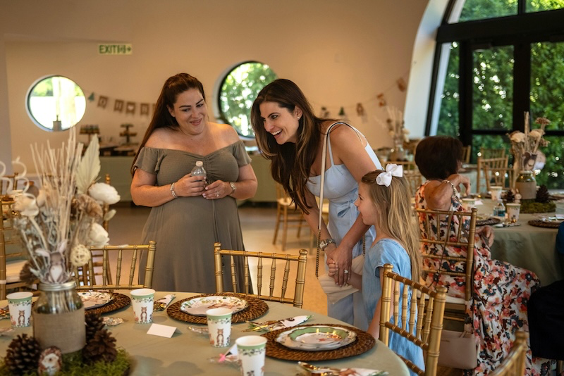 Guests and a host smiling together at a beautifully decorated woodland-themed party, illustrating the seamless and stress-free event planning made possible by online registration and RSVP forms.