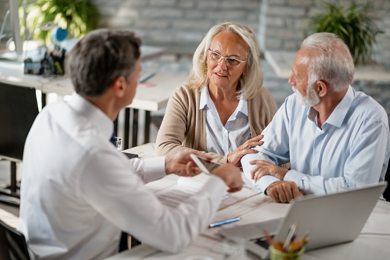 An insurance agent reviewing digital policy forms on a tablet with a senior couple, demonstrating streamlined onboarding and paperless workflows.