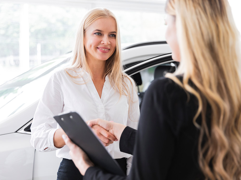 Saleswoman shaking hands with a customer while holding a sales form